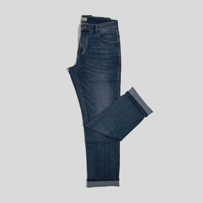 Dark indigo jeans folded with one leg crossed and the hems turned up, on a light grey surface.